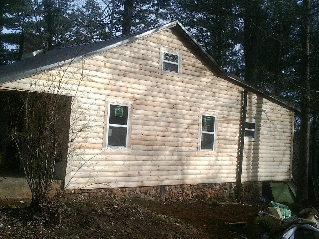 New log siding and dark metal roofing on a gable end in Holly Springs